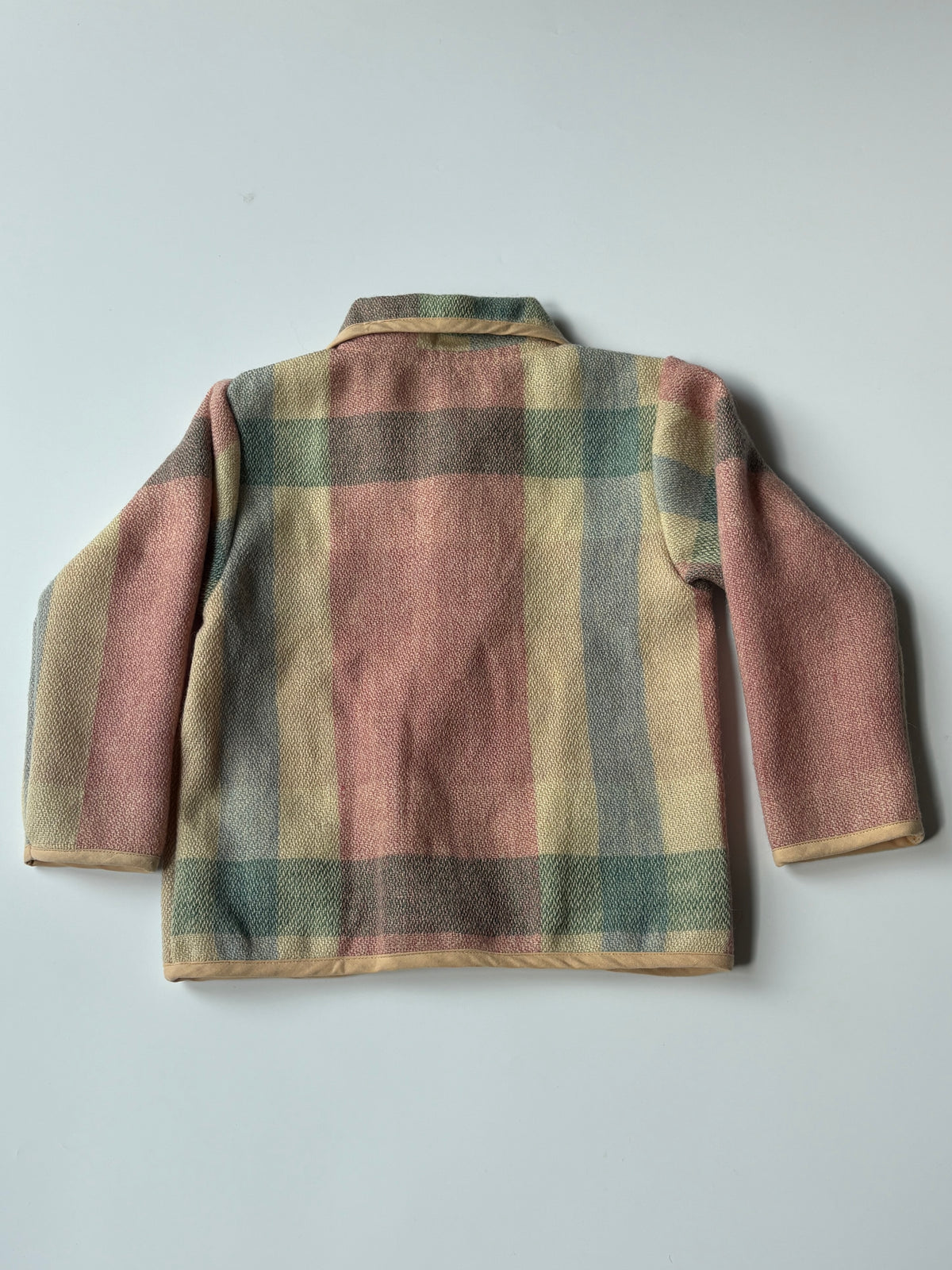 Cream red blue plaid children's blanket jacket, featuring a collar, button closure, and front pockets, laid flat against a light gray background.