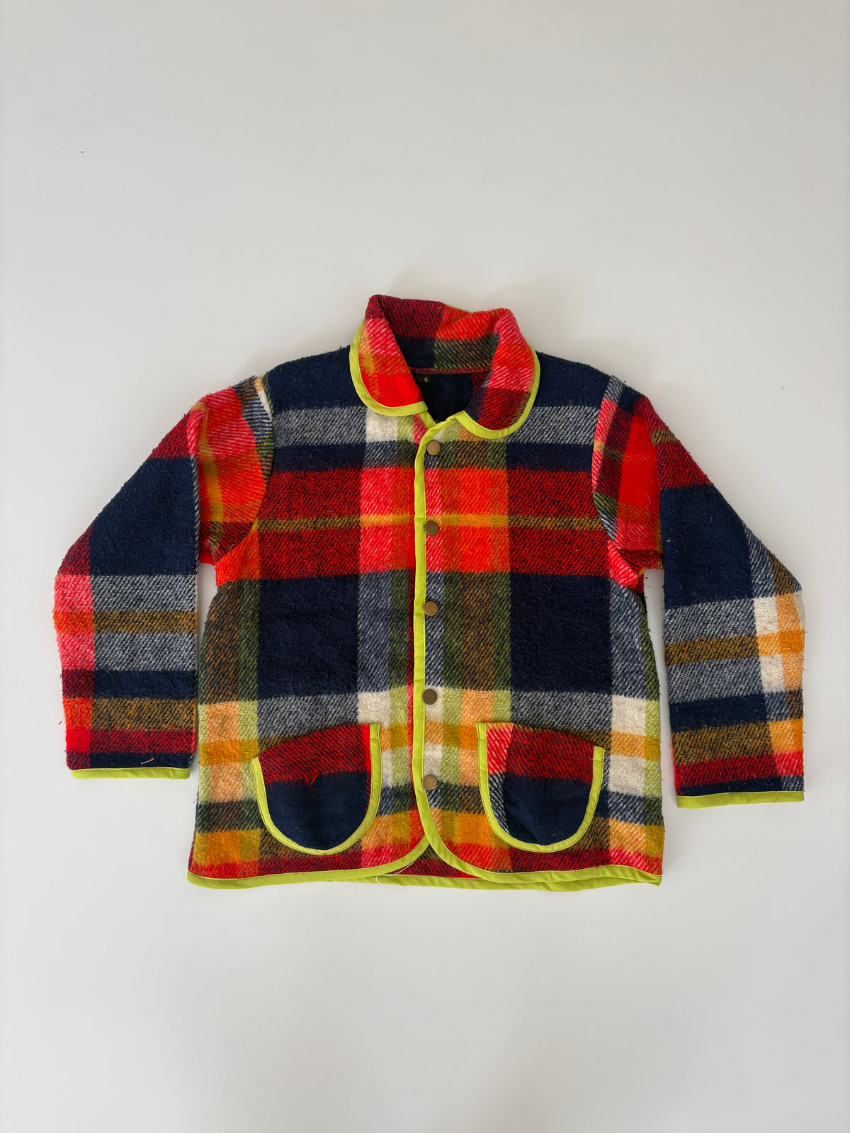 A long-sleeve plaid jacket shown from the back, featuring a vibrant red, navy blue, yellow, and white checkered pattern with a lime green inner lining visible at the collar and cuffs, laid flat against a light gray background.