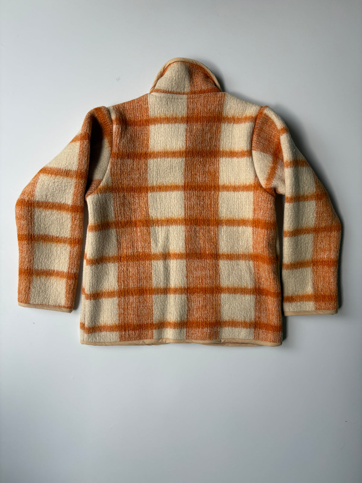 Cream and orange plaid blanket children's jacket. A children's button-front jacket with a warm orange and cream plaid pattern, laid flat on a light gray background.