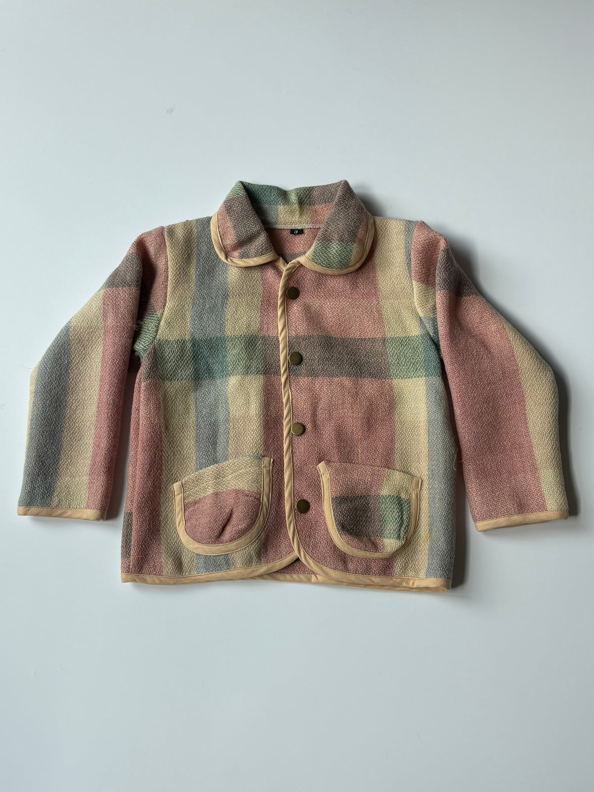Cream red blue plaid children's blanket jacket, featuring a collar, button closure, and front pockets, laid flat against a light gray background.