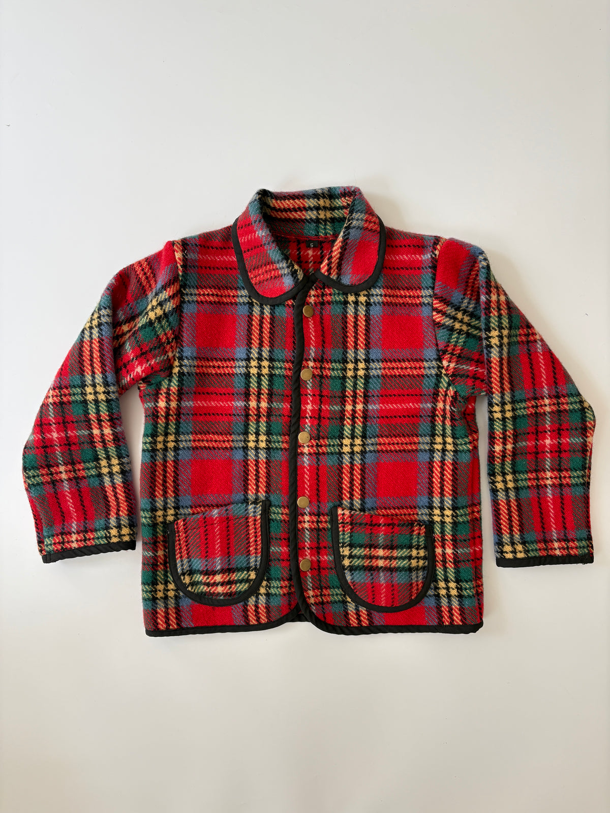 A children's red tartan plaid jacket with green, yellow, and black stripes, featuring a collar, snap-button front, and two front patch pockets, laid flat against a light background.
