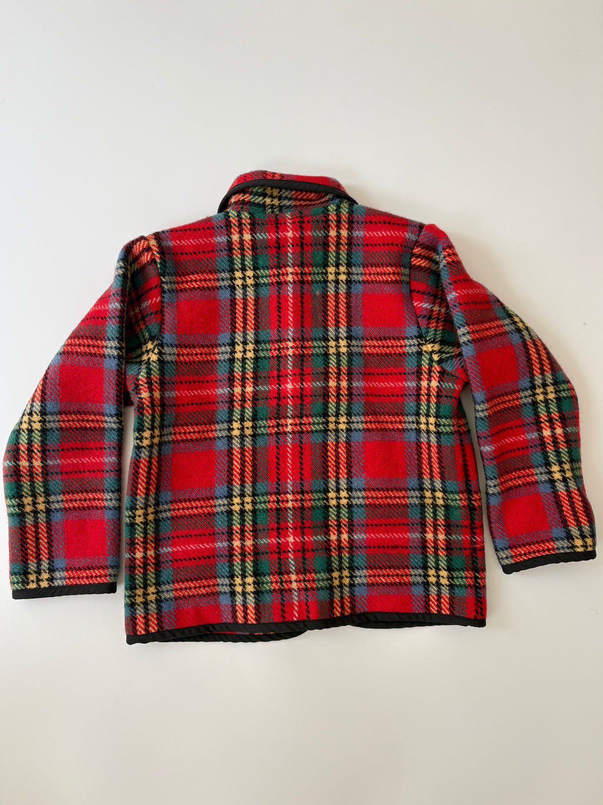 A children's red tartan plaid jacket with green, yellow, and black stripes, featuring a collar, snap-button front, and two front patch pockets, laid flat against a light background.
