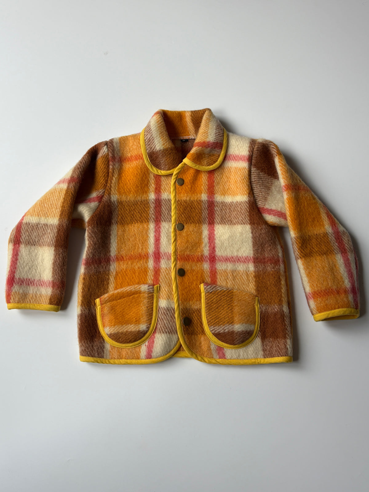 Orange, brown, and cream plaid  children's jacket with yellow trim, laid flat on a light gray background.
