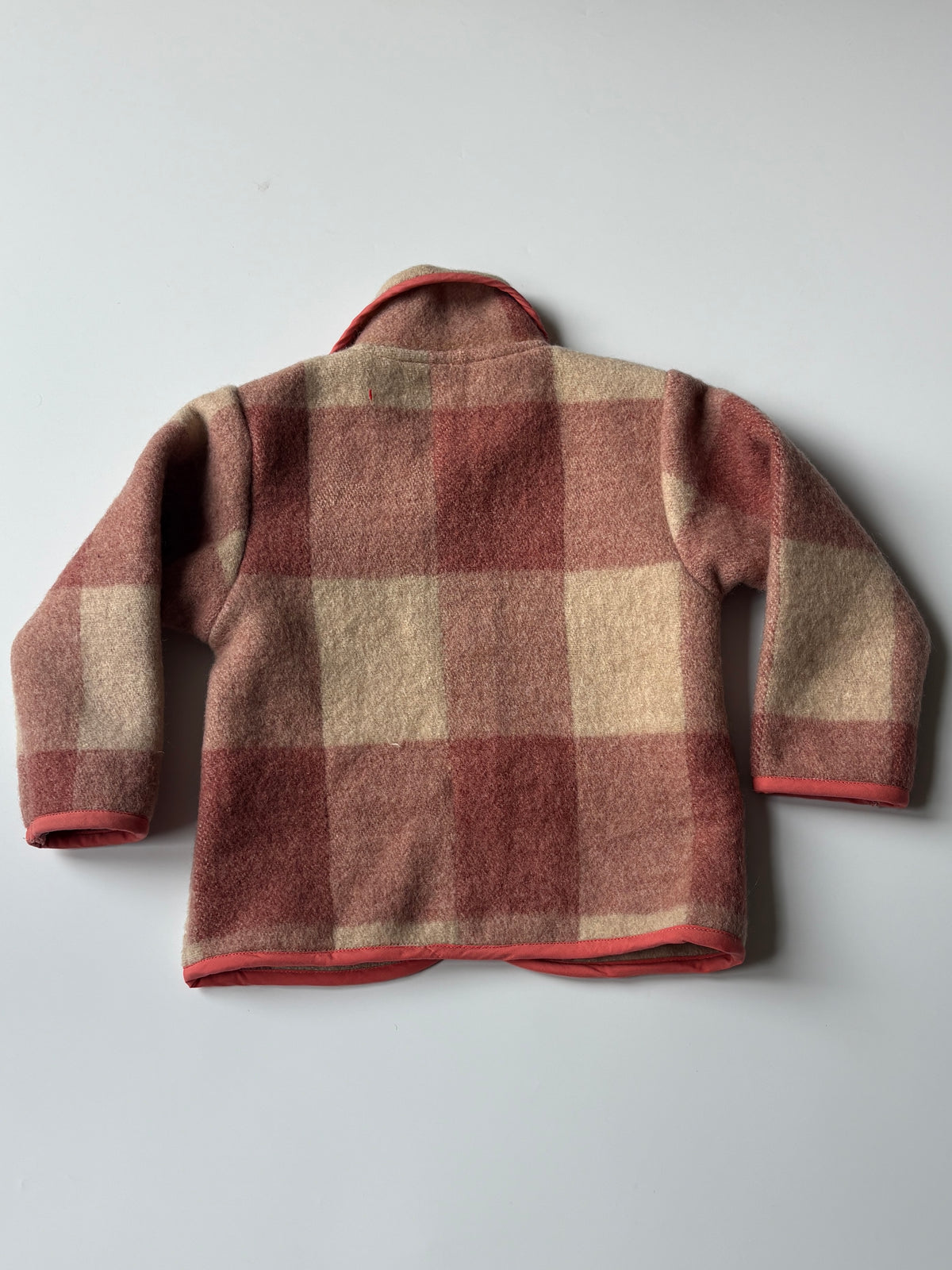 Red and cream plaid blanket children's jacket 1. A children's plaid jacket in muted red and cream with contrasting red trim, shown flat against a light gray background.