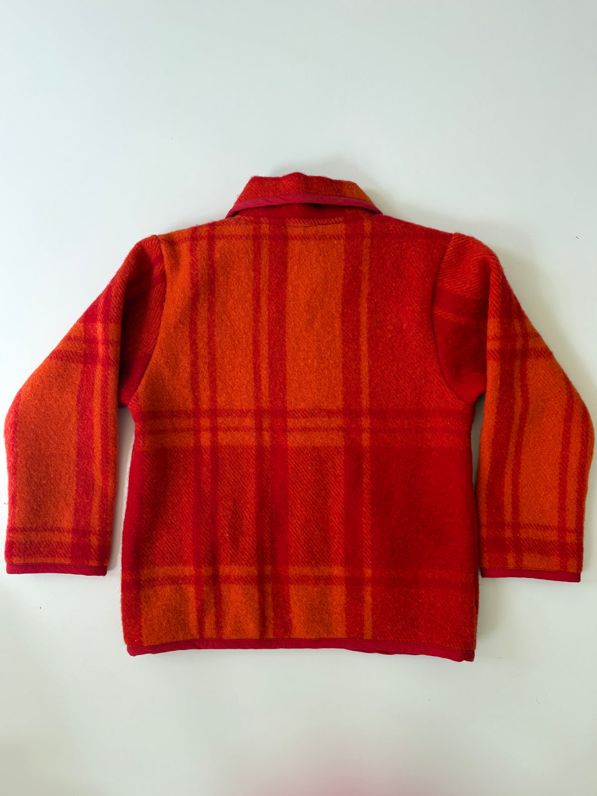 Red and orange plaid children's jacket. 
A red and orange plaid wool-blend jacket with a Peter Pan collar, button front, and two front patch pockets, laid flat against a light background.